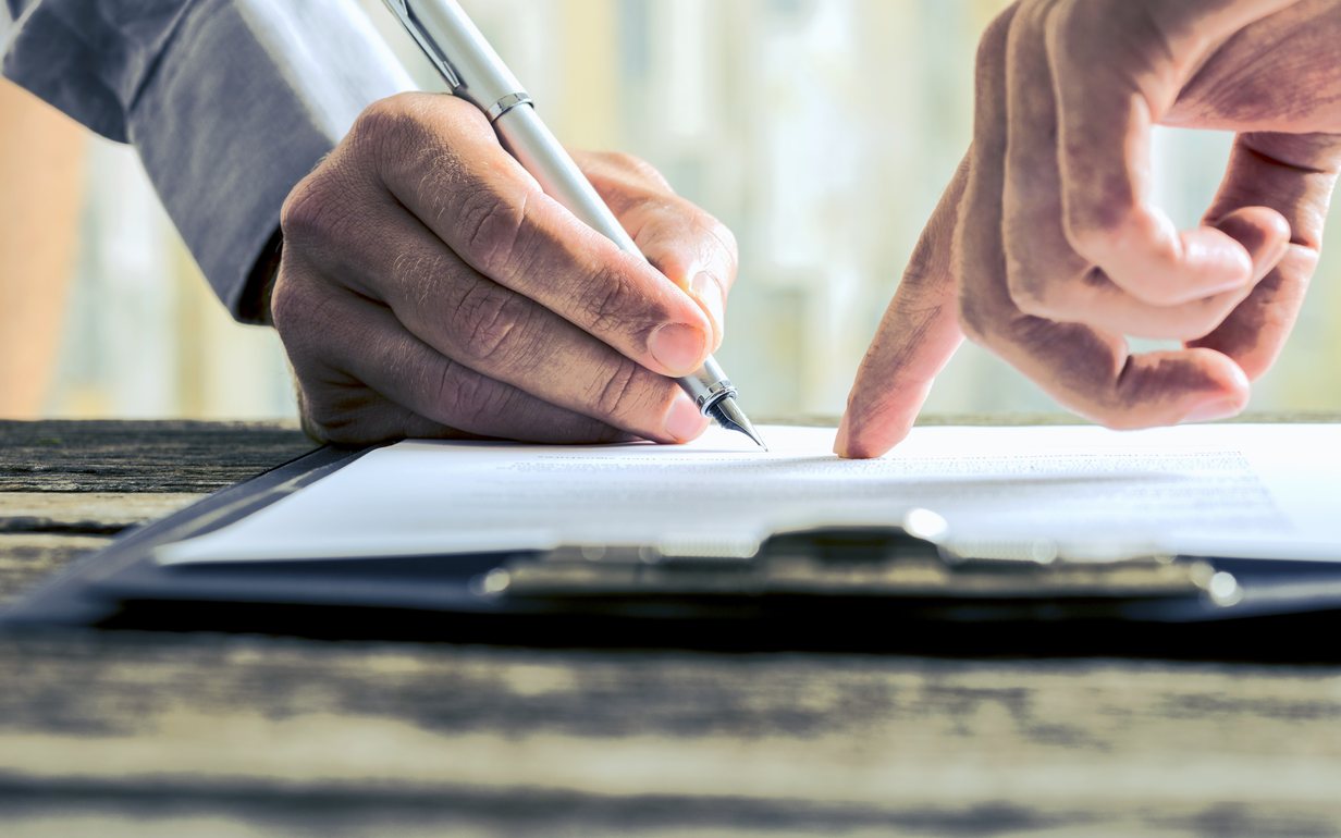 Two people at a desk working through a document together, one indicating a line on the page