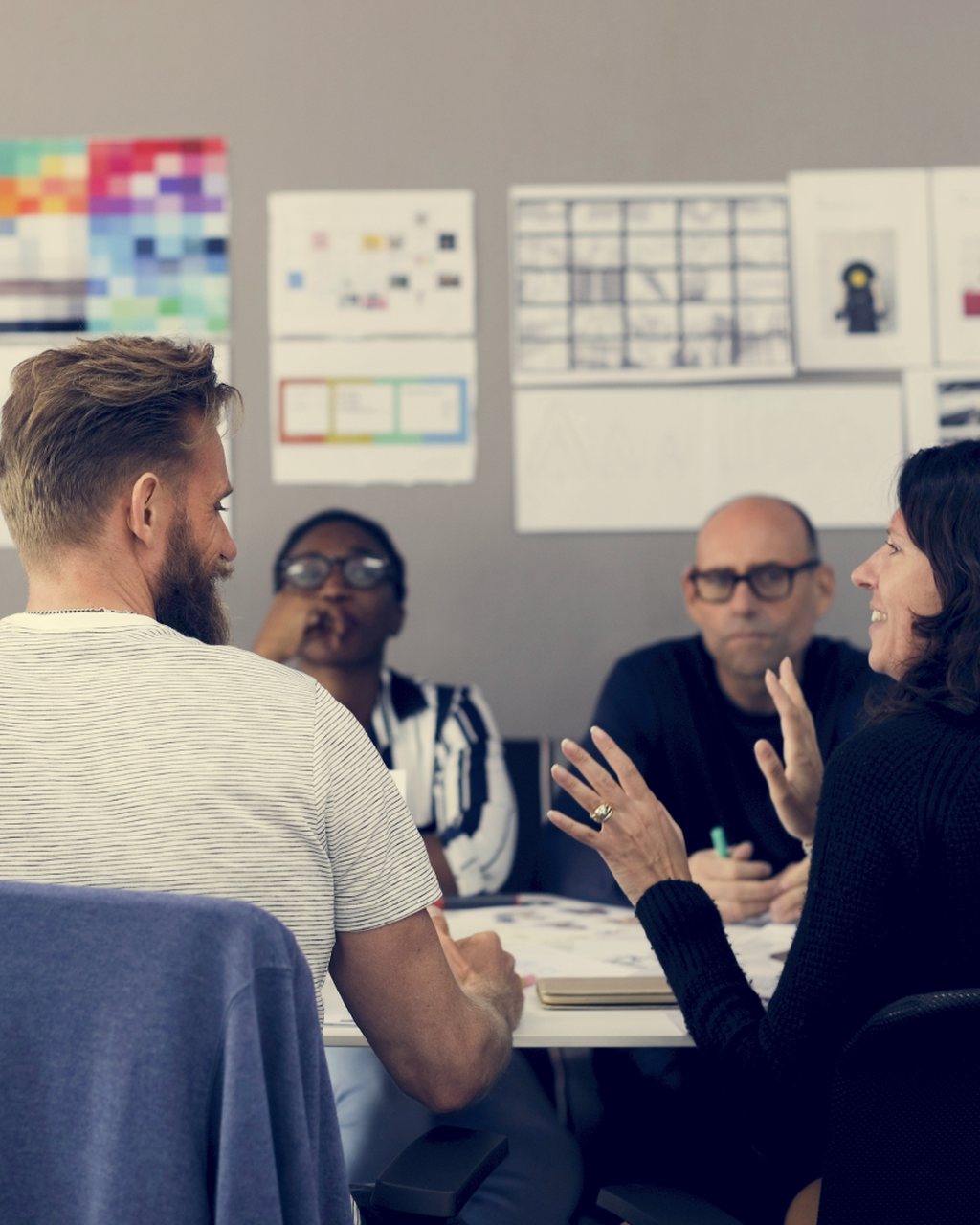A team working through a plan at a table in front of a wall of charts and schedules