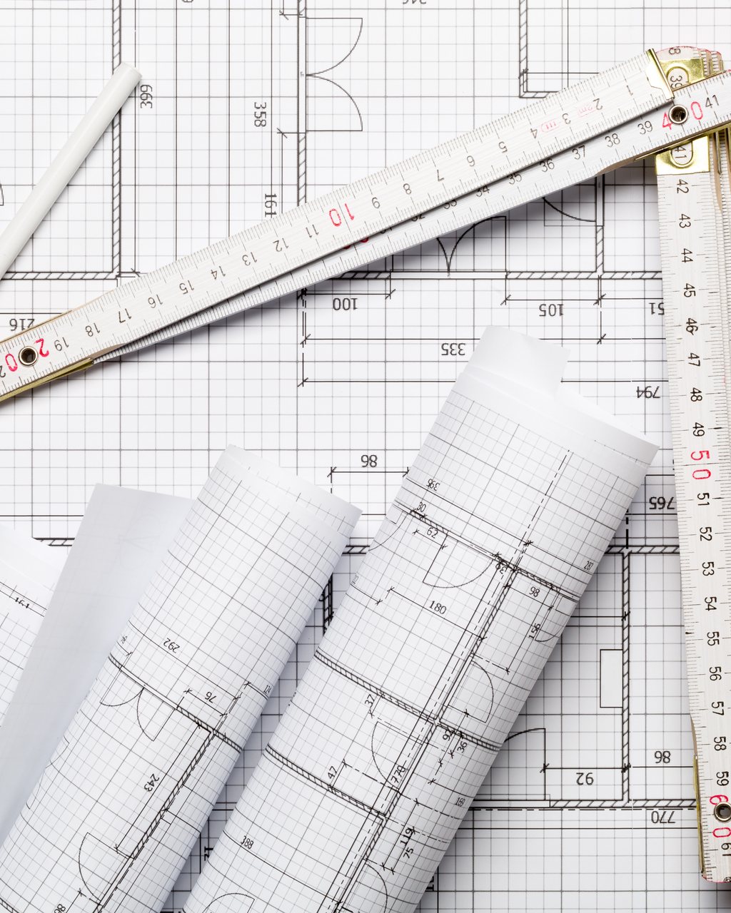 Rolled engineering drawings with a folding rule and dividers on a desk